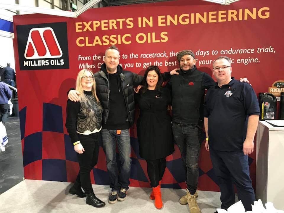 five people in front of millers oils stand at a show