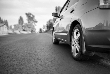Black and white image of a car parked up on the side of the road