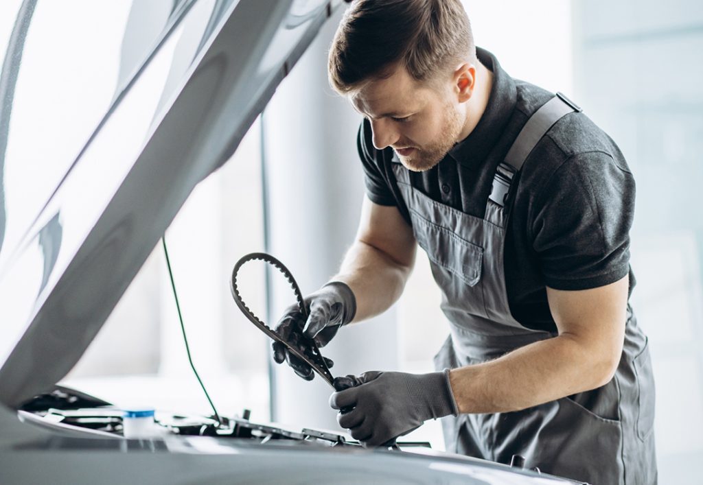 Image of a man replacing the timing belt on a car.