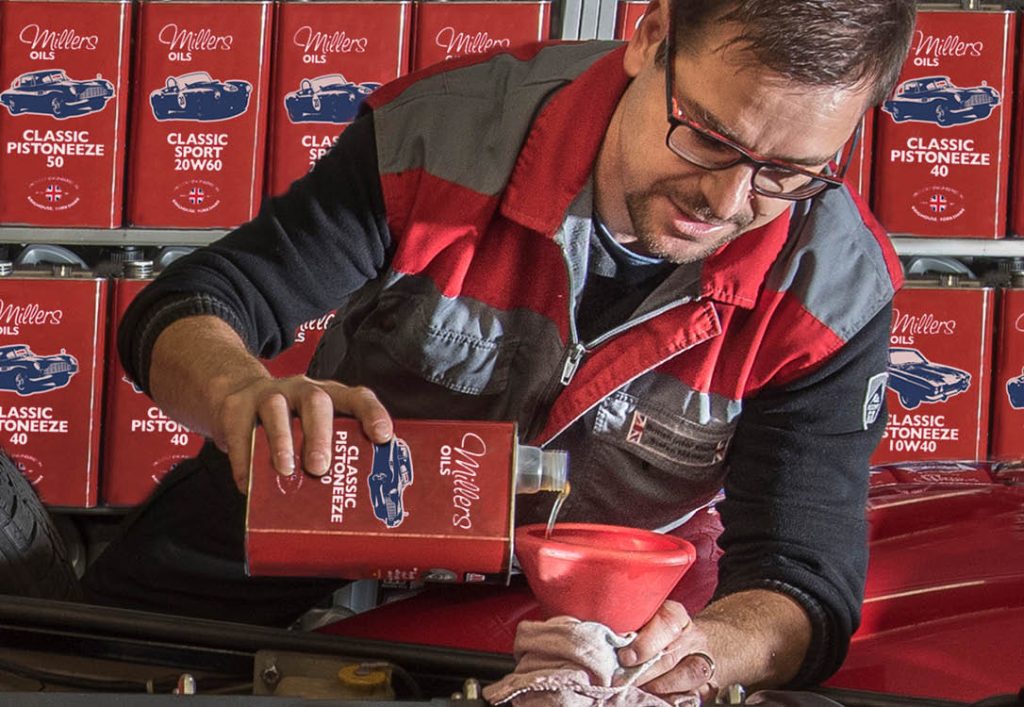 Image of a man pouring Millers oils classic oil into an engine.