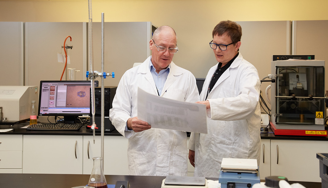 Two people in Millers Oils Laboratory reading oil analysis results